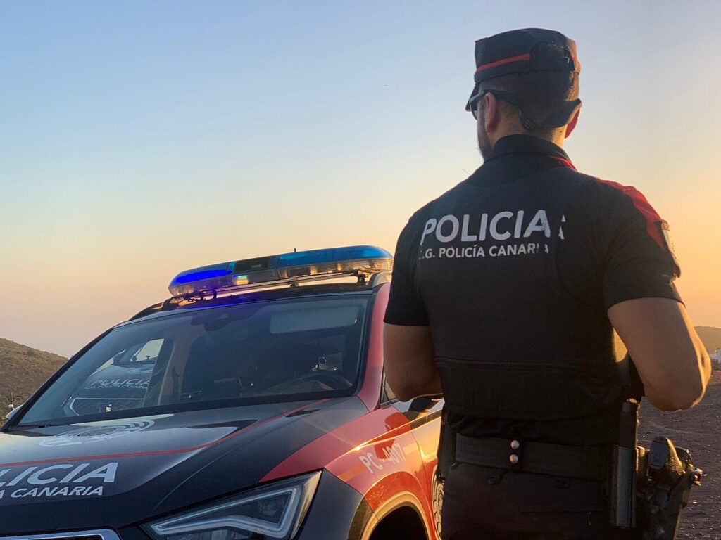 Agente de la Policía Canaria junto a un coche patrulla (imagen de archivo)