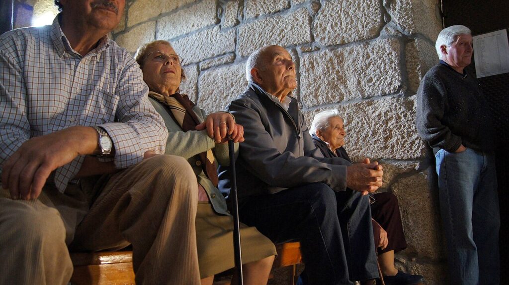 Dos personas mayores conversan sentadas al aire libre